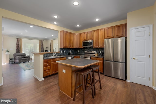 kitchen with dark wood finished floors, dark countertops, appliances with stainless steel finishes, and a sink