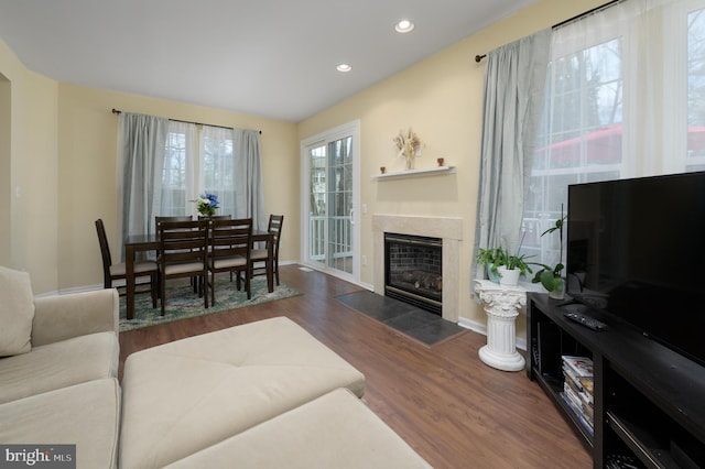 living area featuring a fireplace with flush hearth, baseboards, wood finished floors, and recessed lighting