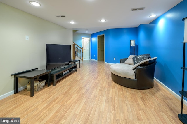 living area featuring wood finished floors, visible vents, baseboards, and stairway
