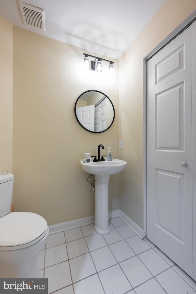 half bath featuring tile patterned floors, baseboards, visible vents, and toilet
