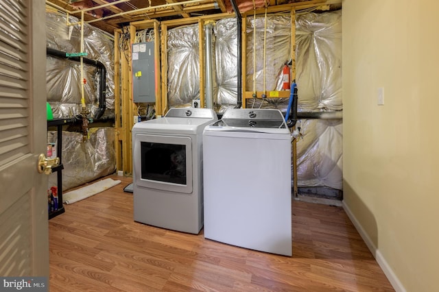 laundry room featuring wood finished floors, electric panel, laundry area, and separate washer and dryer