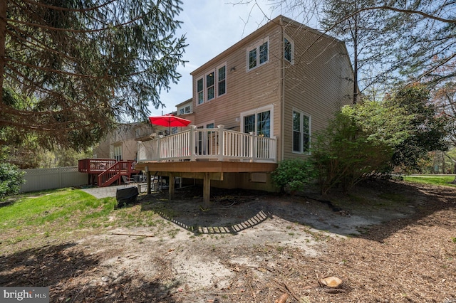 rear view of property featuring a wooden deck, stairs, and fence