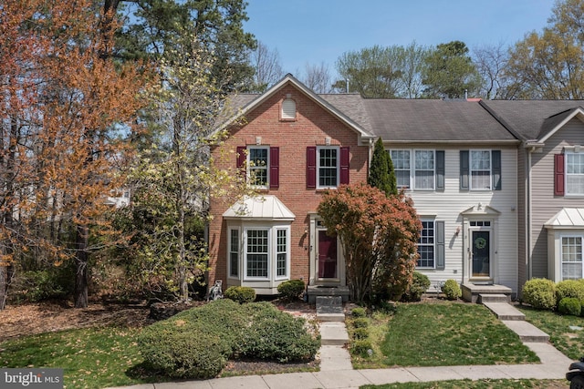 view of front facade with brick siding and a front lawn