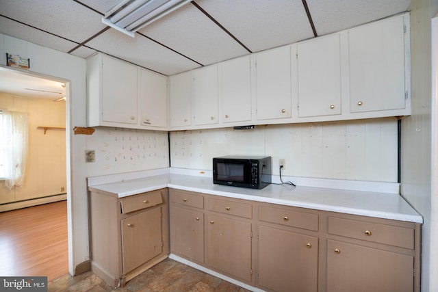 139 Kimport Ave, Boalsburg, PA 16827 - kitchen featuring black microwave, a drop ceiling, a baseboard heating unit, light countertops, and white cabinetry