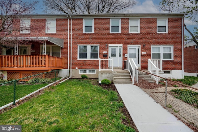 townhome / multi-family property with a front lawn, fence, and brick siding