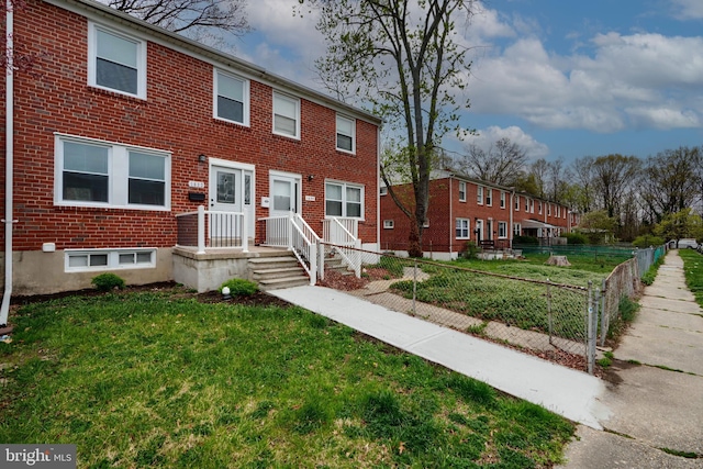view of property with brick siding, fence private yard, and a front lawn
