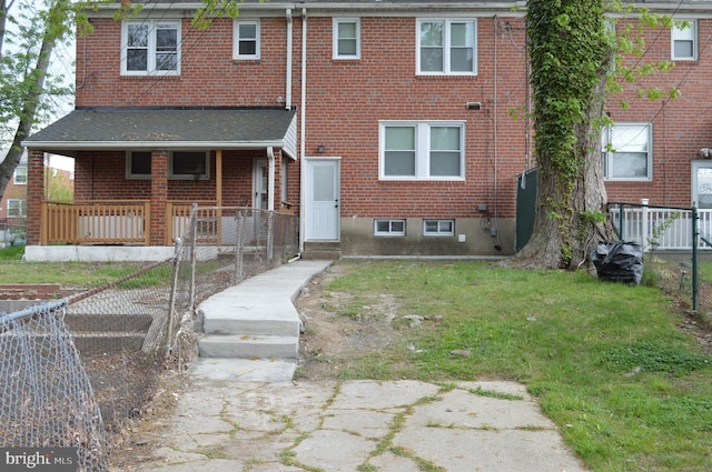 view of front of house featuring brick siding, fence, a porch, and a front yard