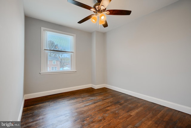 empty room featuring a ceiling fan, dark wood-style floors, and baseboards