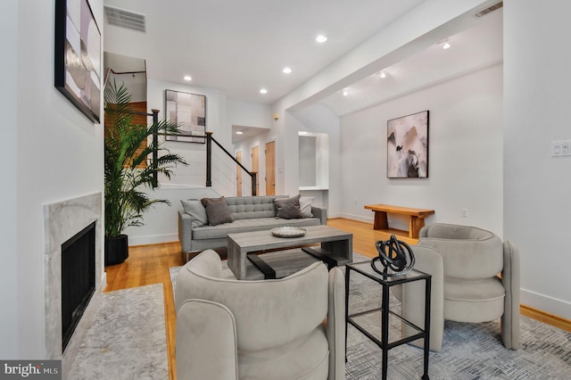 living room with visible vents, baseboards, wood finished floors, and stairway