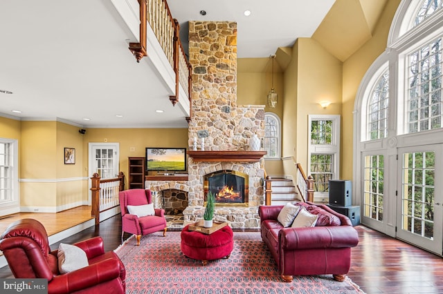 living area with baseboards, ornamental molding, a fireplace, high vaulted ceiling, and hardwood / wood-style flooring