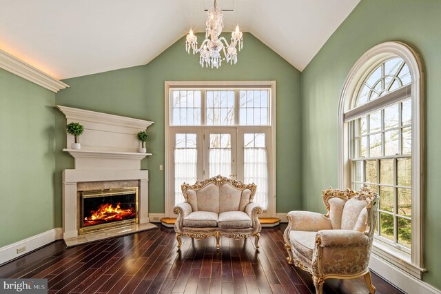 sitting room with a fireplace, dark wood-type flooring, a notable chandelier, and lofted ceiling