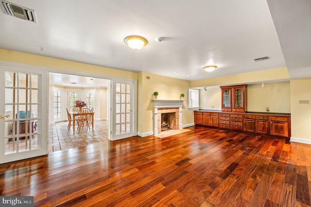 unfurnished living room featuring a tiled fireplace, visible vents, and dark wood-style flooring