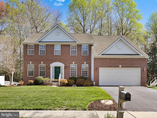 view of front of property with concrete driveway, a front yard, brick siding, and an attached garage