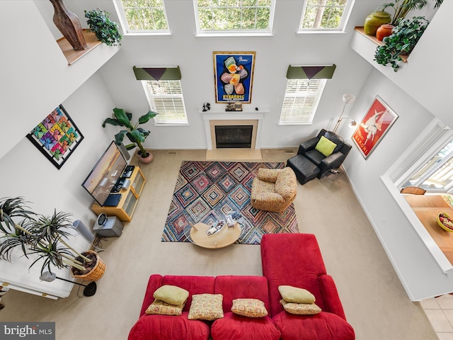 living area with baseboards, a towering ceiling, and a fireplace with flush hearth