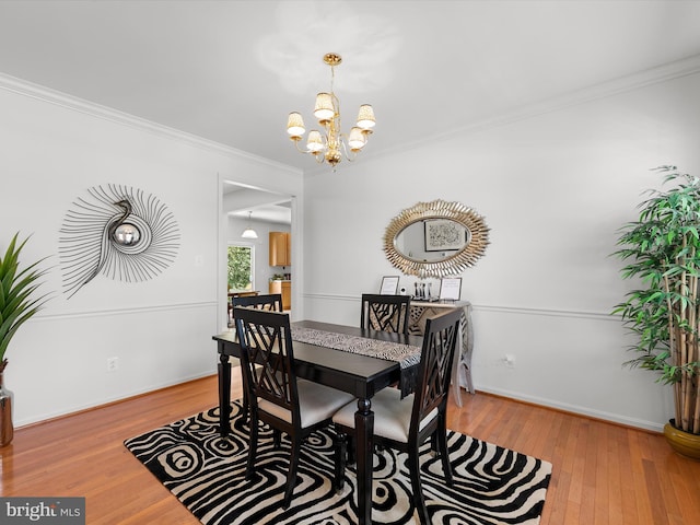 dining area with a notable chandelier, baseboards, hardwood / wood-style floors, and crown molding