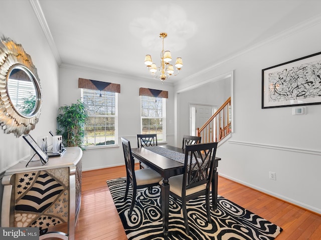 dining space featuring hardwood / wood-style floors, a notable chandelier, baseboards, and crown molding