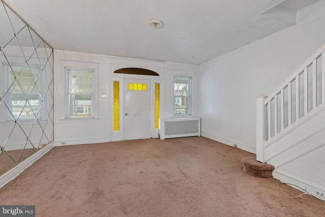 entryway featuring radiator heating unit, baseboards, carpet, and stairway