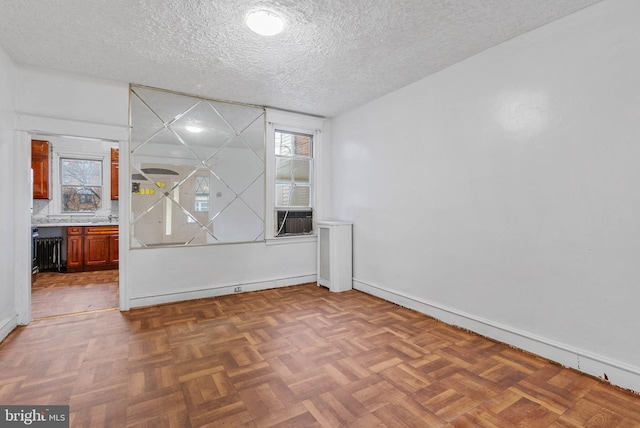 spare room featuring a textured ceiling and baseboards