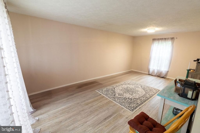 unfurnished living room with a textured ceiling, baseboards, and wood finished floors