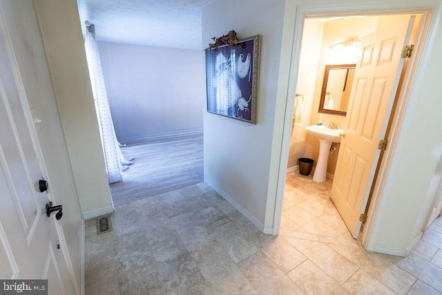 hall featuring a sink and baseboards