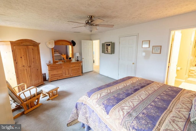 bedroom with a textured ceiling, carpet flooring, ceiling fan, and ensuite bath