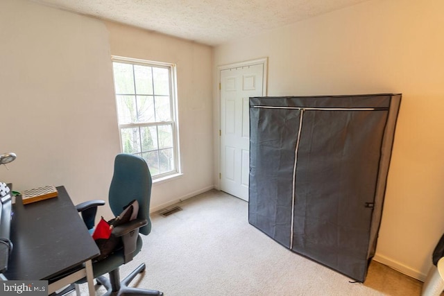 office featuring visible vents, baseboards, light carpet, and a textured ceiling