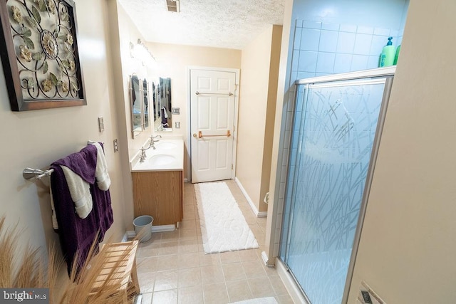 bathroom featuring tile patterned floors, vanity, a textured ceiling, and a stall shower