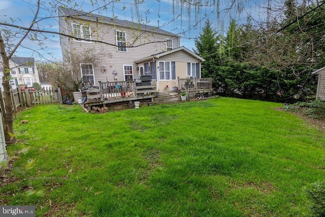 rear view of house with a wooden deck, a fenced backyard, and a lawn