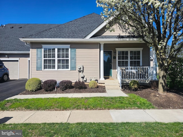 view of front of property with a porch, a shingled roof, an attached garage, and driveway