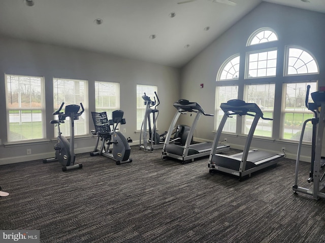 workout area featuring high vaulted ceiling, baseboards, and dark carpet