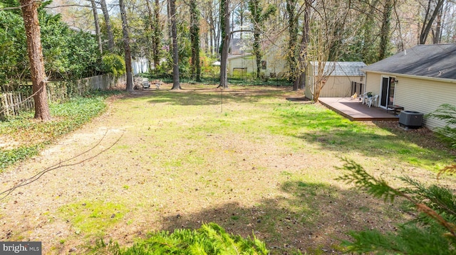 view of yard with a deck, fence, central air condition unit, a shed, and an outbuilding