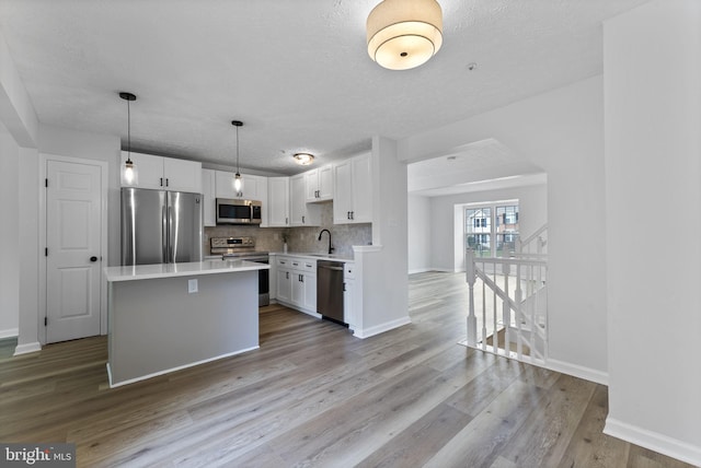 kitchen featuring baseboards, light countertops, white cabinetry, appliances with stainless steel finishes, and a sink