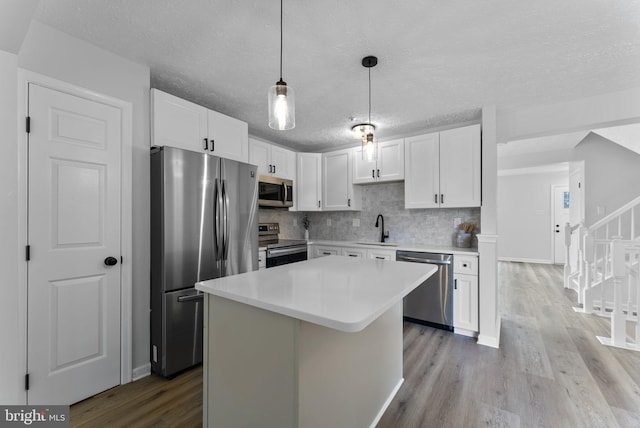 kitchen featuring a textured ceiling, white cabinets, light wood-style floors, stainless steel appliances, and a sink