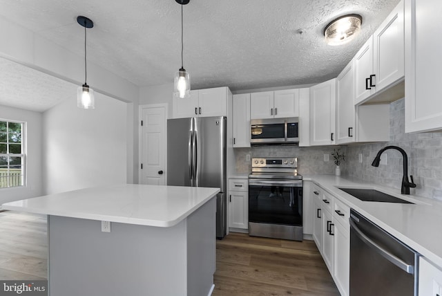 kitchen featuring tasteful backsplash, a sink, a textured ceiling, wood finished floors, and stainless steel appliances