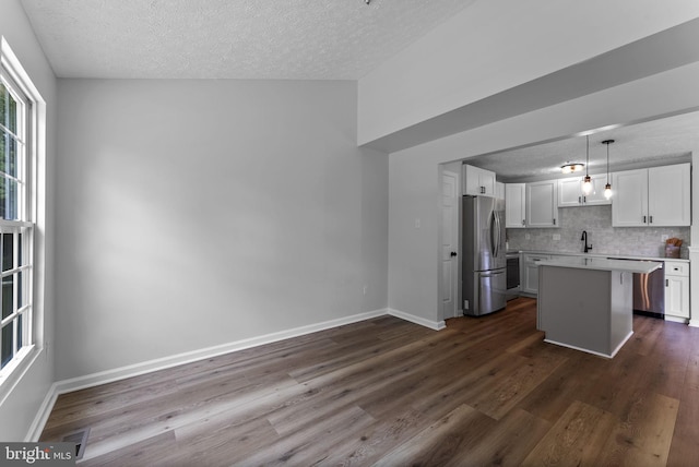 kitchen with a textured ceiling, light countertops, dark wood finished floors, and stainless steel appliances