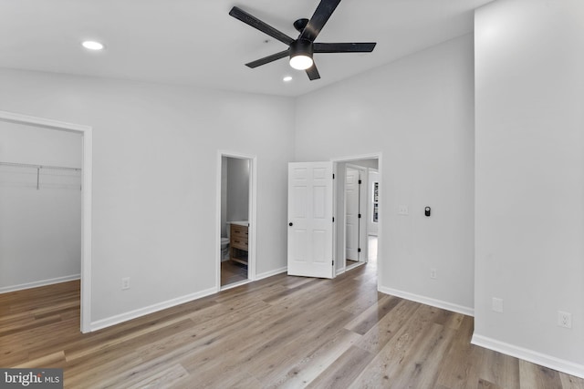 unfurnished bedroom featuring wood finished floors, baseboards, lofted ceiling, and a walk in closet