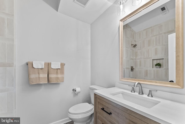 bathroom with visible vents, toilet, tiled shower, and vanity