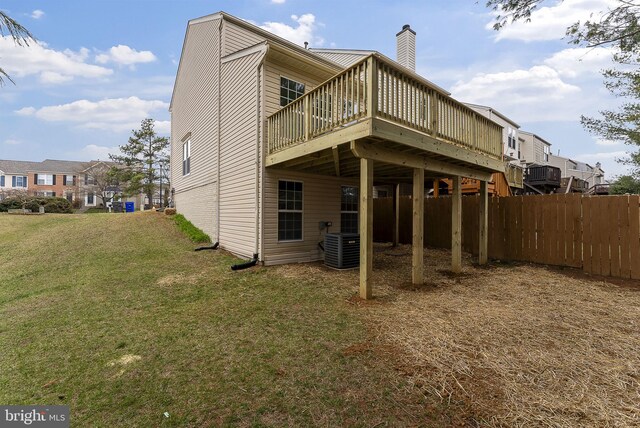 rear view of property featuring a chimney, central AC, a deck, fence, and a lawn