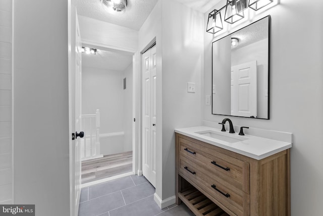 bathroom with vanity, baseboards, tile patterned flooring, and a textured ceiling