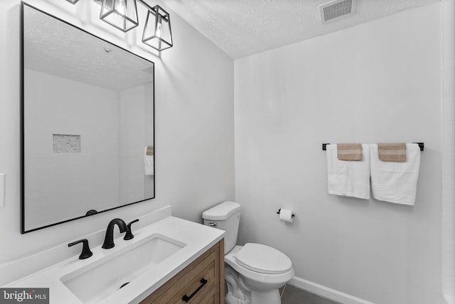 bathroom featuring vanity, baseboards, a textured ceiling, toilet, and visible vents