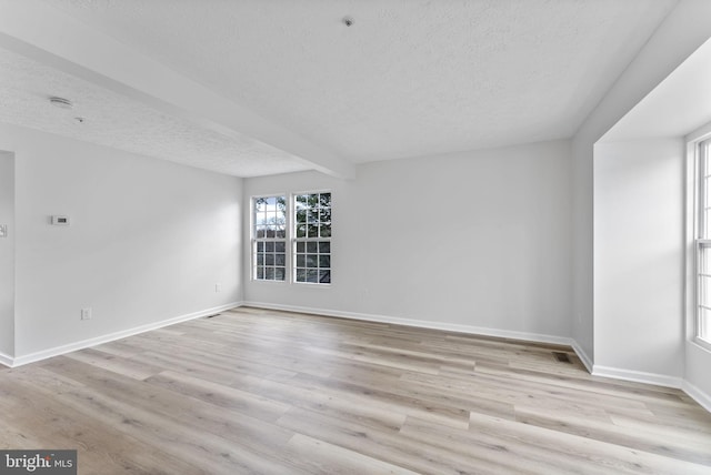 empty room featuring a textured ceiling, wood finished floors, and baseboards