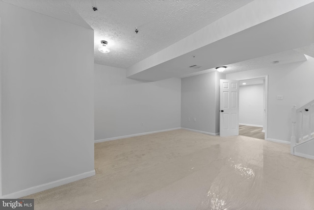 finished below grade area with a textured ceiling, carpet flooring, and baseboards