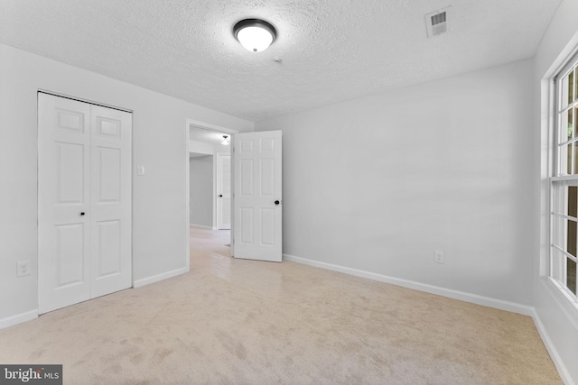 unfurnished bedroom featuring a closet, baseboards, carpet flooring, a textured ceiling, and visible vents