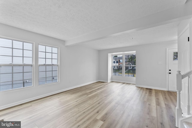 unfurnished living room with baseboards, stairs, wood finished floors, and a textured ceiling