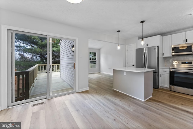 kitchen with visible vents, appliances with stainless steel finishes, a textured ceiling, light wood finished floors, and white cabinetry