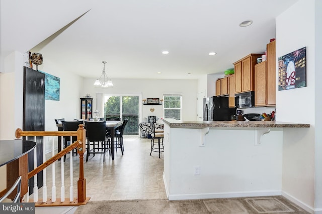 904 Emerson Ct, Clementon, NJ 08021 - kitchen with a peninsula, hanging light fixtures, brown cabinets, a kitchen bar, and black appliances