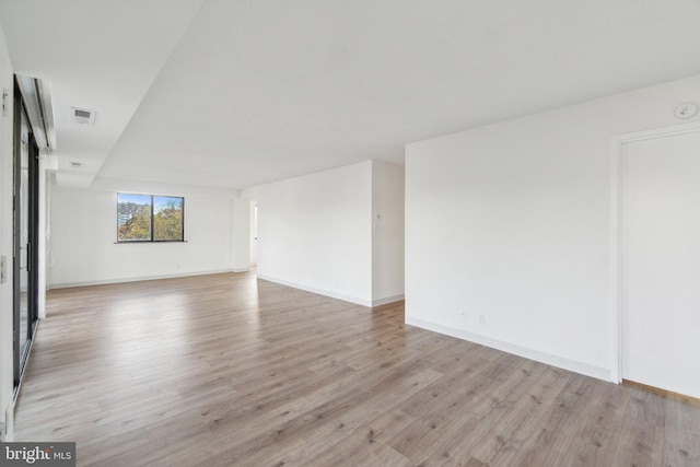 empty room featuring light wood finished floors, baseboards, and visible vents