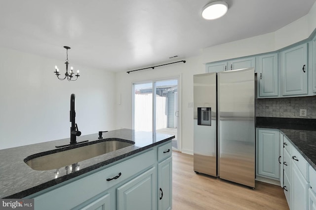 kitchen featuring backsplash, dark stone counters, a sink, and stainless steel fridge with ice dispenser