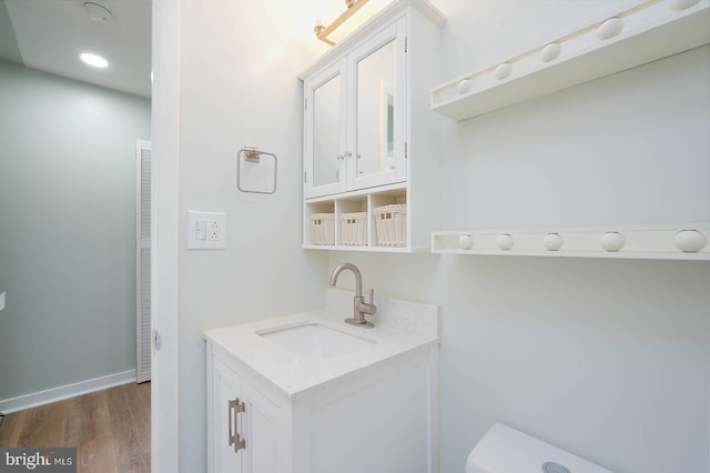 bathroom with wood finished floors, toilet, vanity, baseboards, and a heating unit