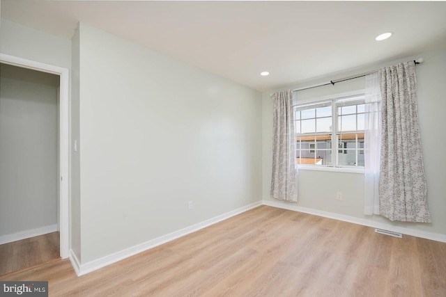 empty room featuring visible vents, baseboards, and wood finished floors